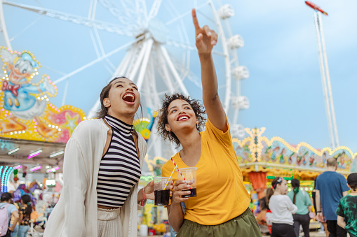 Portrait of cheerful women having fun at the amusement park. They are talking, laughing and drinking. A sense of freedom and liberation.