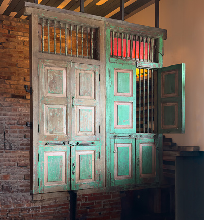 Feature wall constructed of weathered doors with peeling paint and antique hardware suspended in front of antique brick wall.