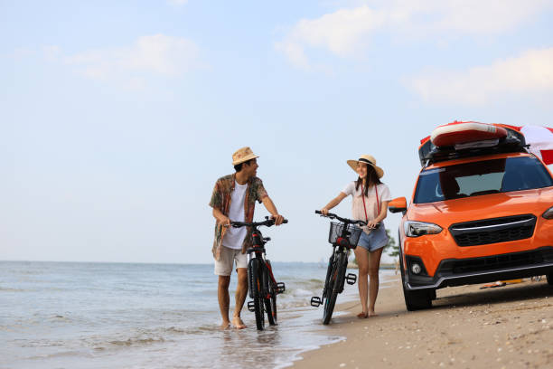 istock A Young Couple with Bikes at the Beach in an orange car background, Selectively focus on sports vehicle against a young couple walk relaxation on the beach 1630299740