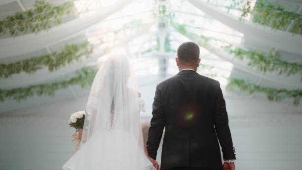 istock Bride and groom holding hands and walking 1630316697
