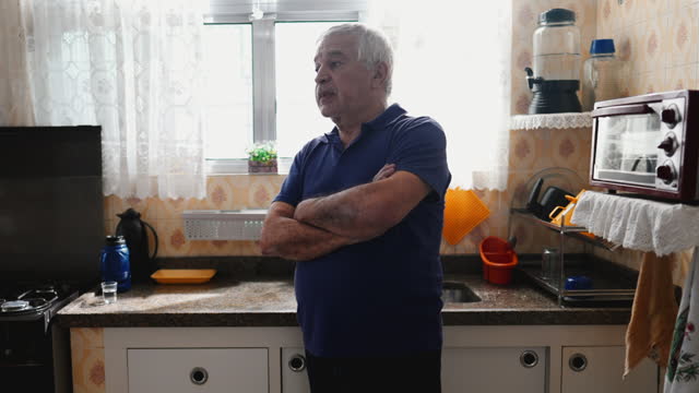 Thoughtful Elderly Man in Kitchen, Deep Reflection and Dilemma Scene. Worried emotion struggling with decision by window