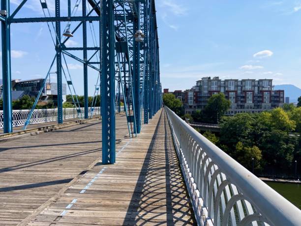 Low angle view of a pedestrian walking across a vibrant blue bridge in london, england, on a sunny day