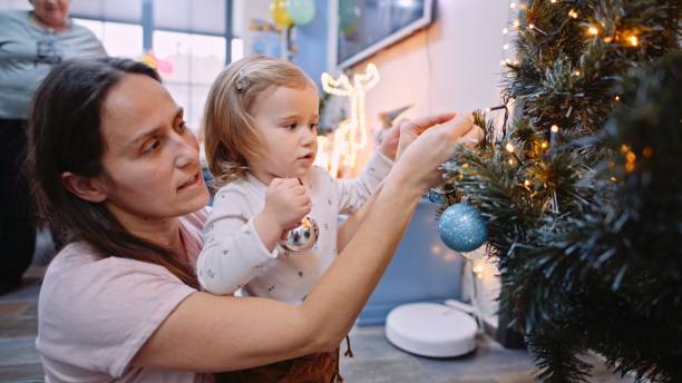 istock Mom and kid decorating Christmas tree at home. 1630421623