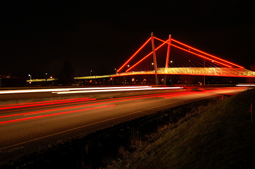 Neon streaks on highway with illuminated bridge