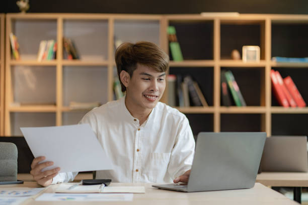 istock Asian young man doing accounting work using app and financial documents calculating salary of company employees and meeting online. 1630481703