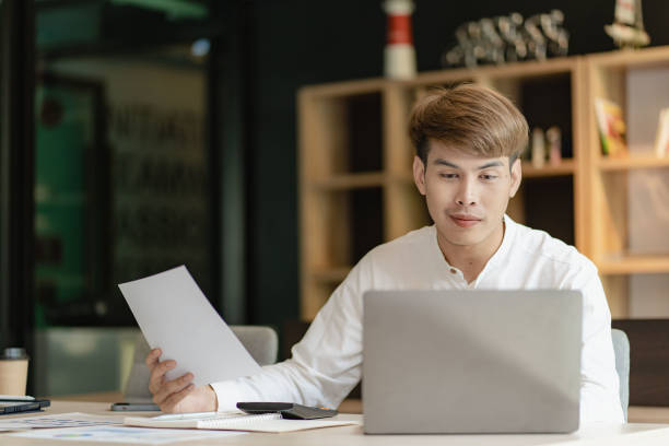 istock Asian young man doing accounting work using app and financial documents calculating salary of company employees and meeting online. 1630481706