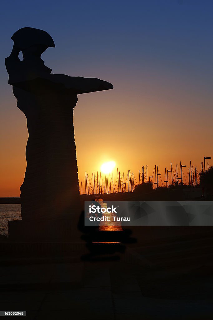 Sunset at the harbor sunset on the harbor with a silhouette of a statue Beach Stock Photo