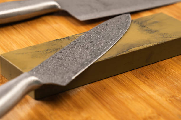 istock Sharpening knives with a Whetstone. Knife sharpening. Sharp knife and sharpening stone on a wooden cutting board. 1630540717