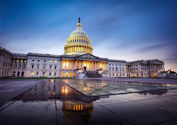 Capitol building in Washington DC illuminated against a stormy sky