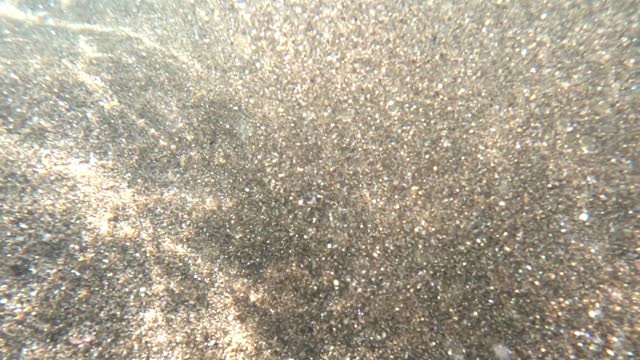 Abstract background sparkling gold mica sand underwater in sea