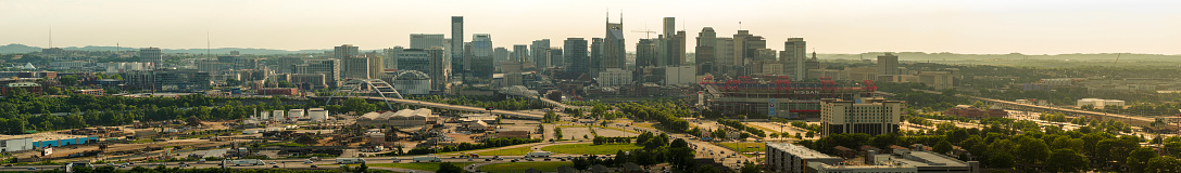 Downtown Nashville, Tennessee skyline with skyscrapers and road bridges in sunset beams against dramatic sky. Aerial view