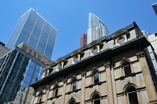 A bank building from the 1870s on King Street in Toronto, with modern financial district skyscrapers in the  background