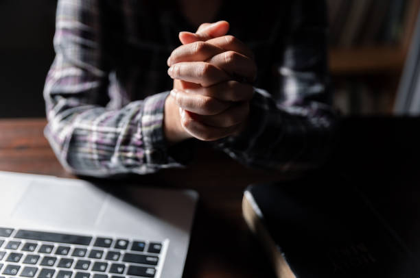 istock Christian online technology concept. Hands praying of christian with digital computer laptop, Online live church for sunday service. Asian catholic man are reading Holy bible book and online study. 1630679134