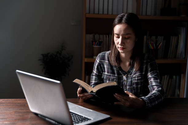 istock Christian online technology concept. Hands praying of christian with digital computer laptop, Online live church for sunday service. Asian catholic man are reading Holy bible book and online study. 1630732441