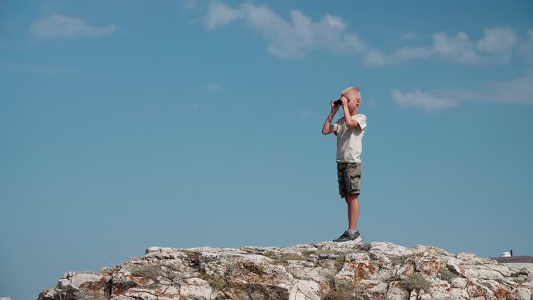 A young hiker inspects the surroundings through binoculars