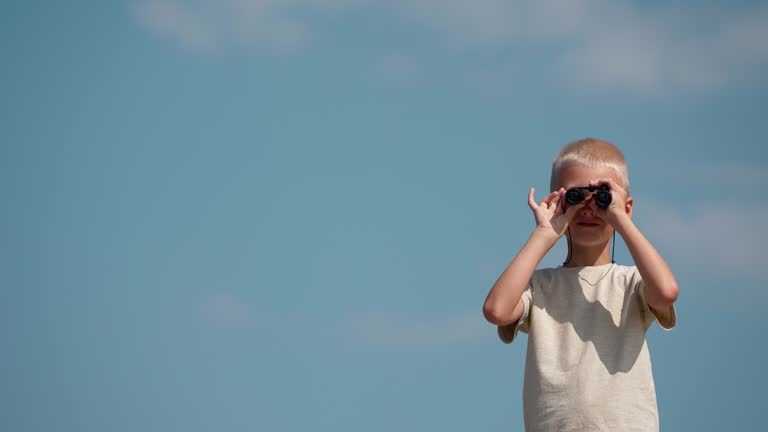 Portrait of a schoolboy looking through binoculars directly into the camera