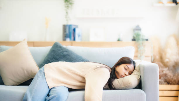 istock Asian woman resting at home on couch, feeling exhausted after work, lacking energy, or overworked, too tired, and lacking motivation 1630737730