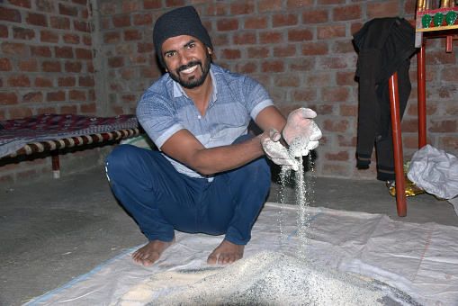 Indian farmer mixing different fertilizer elements in manure, at home. selective focus