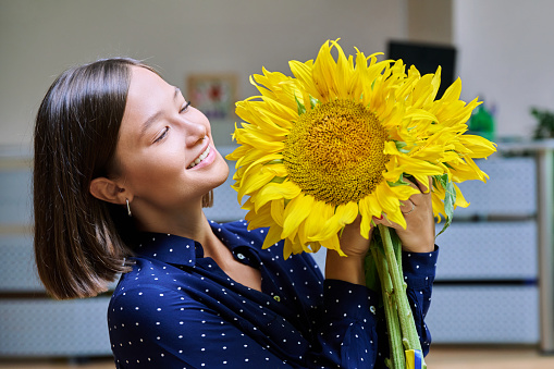 Young happy smiling woman with bouquet of yellow sunflower flowers. Summer season, the beauty of nature and the beauty of a young female