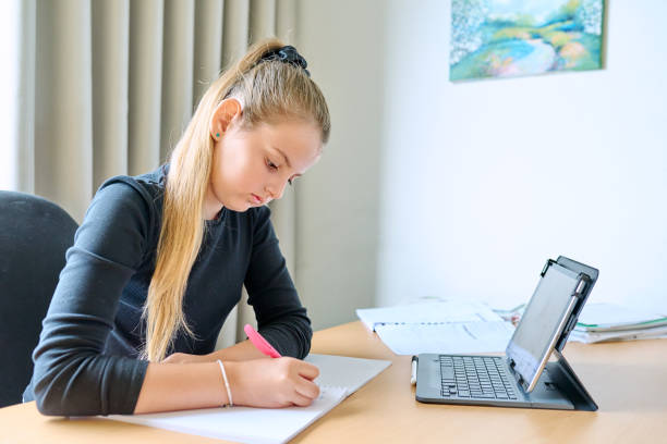 istock Girl child studying at home, sitting at her desk using digital tablet 1630756522