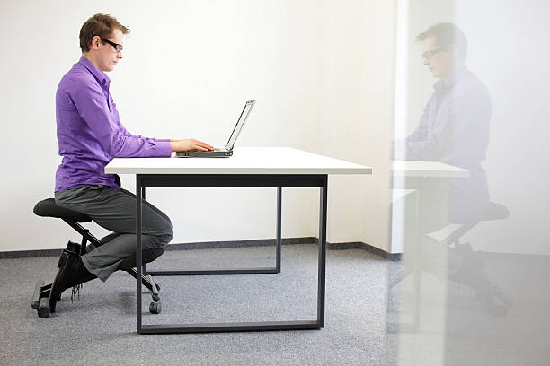 istock correct sitting position at workstation. man on kneeling chair 163076214