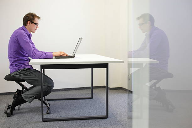 istock bad sitting posture at workstation. man on kneeling chair 163076270
