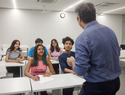 Computer science teacher giving a lecture to her high school students in the classroom.