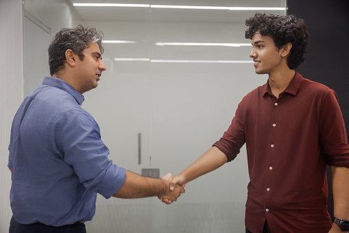 A confident college student with an interviewer shaking hands