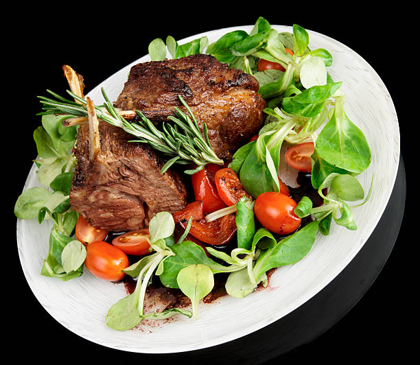 rari fritte di agnello isolato su sfondo nero - salad lettuce animal bone brown foto e immagini stock