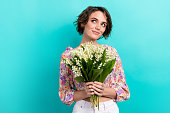 Portrait of cheerful nice girl dressed flower print blouse holding flower bouquet look empty space isolated on teal color background