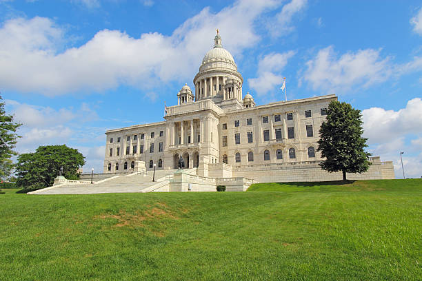 The Rhode Island State House on Capitol Hill in Providence Front view of the Rhode Island state capitol building and lawn on Capitol Hill in Providence with bright blue sky and white clouds in the background. The building is covered with white Georgia marble and was constructed from 1895 to 1904. providence rhode island stock pictures, royalty-free photos & images