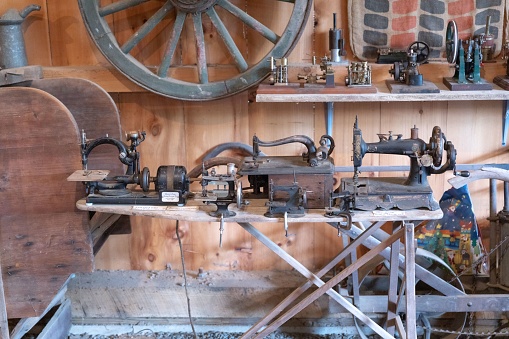 A variety of old-fashioned sewing machines and antiques inside a rustic wooden barn in New England