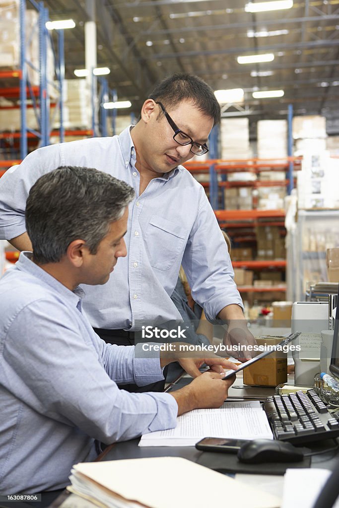 Business Colleagues Working At Desk In Warehouse Male Business Colleagues Working At Desk In Warehouse Freight Transportation Stock Photo