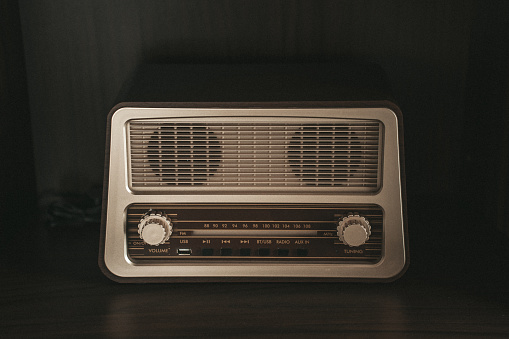 Closeup of vintage radio on wooden table with yellow wall
