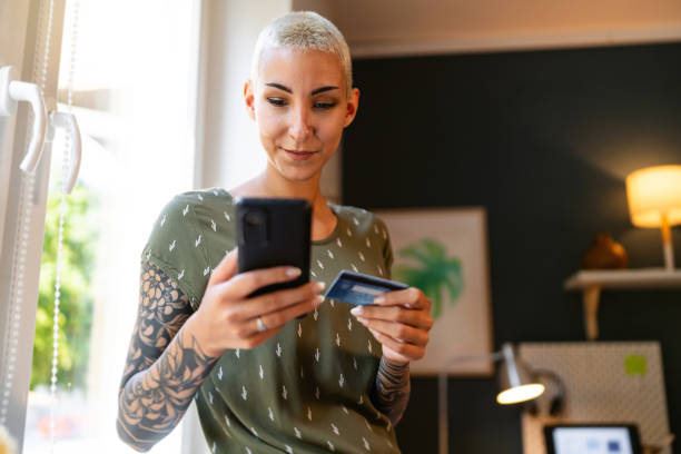 istock Young woman holding credit card and using mobile phone while online shopping 1630947668