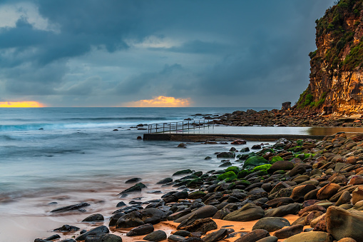 Rainy day sunrise with overcast sky and small waves at  Macmasters Beach on the Central Coast, NSW, Australia.