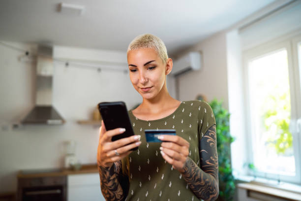 istock Young Caucasian woman using mobile phone while online shopping 1630953364