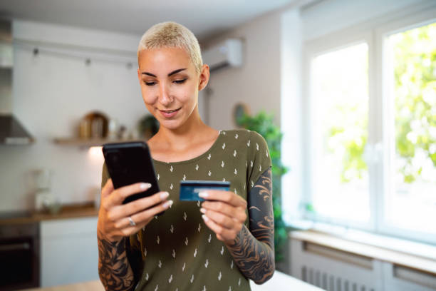 istock Young Caucasian woman using mobile phone while online shopping 1630953397
