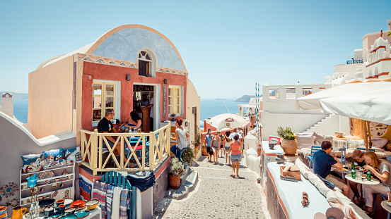Oia village with numerous gift shops and cafes; Cyclades islands in the background.