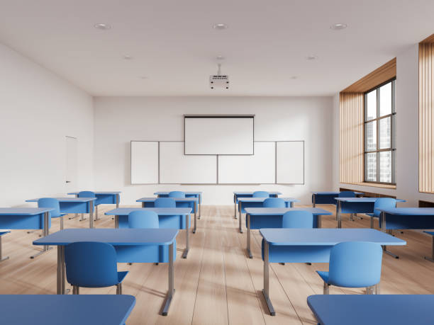 istock Cozy classroom interior with desk in row and blackboard with screen, window 1630982465