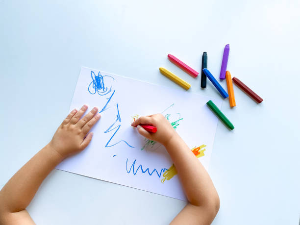 istock small child draws with pastel crayons on white table. 1630991640