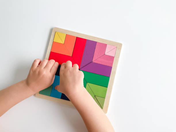 子供の手は白い背景に色とりどりの木のモザイクを集める。 - board game piece 写真 ストックフォトと画像