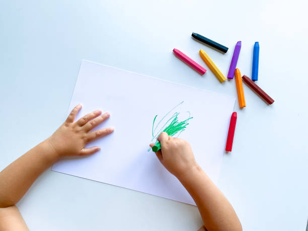 istock small child draws with pastel crayons on white table. 1630991642