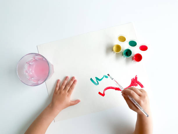 istock small child draws with paints and brush on white table. 1630991648
