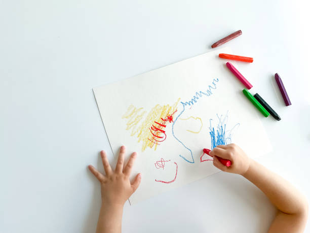 istock small child draws with pastel crayons on white table. 1630991652