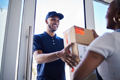 Ecommerce, happy delivery man with box and woman at her front door. Online shopping or logistics, supply chain or distribution and African female person receive her cardboard parcel with smile