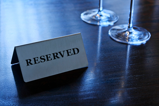 This table is already reserved! In a restaurant on a dark brown wooden table is a sign with the inscription 