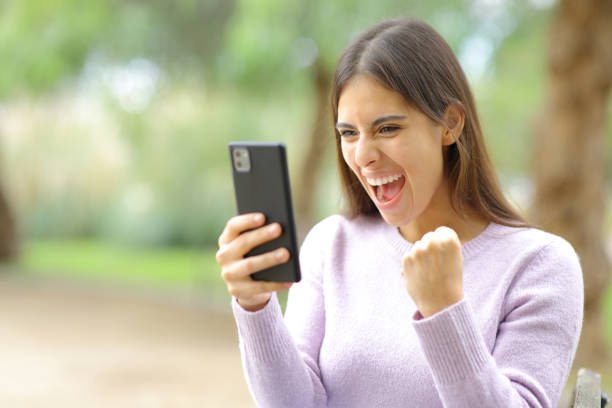 istock Excited woman celebrating watching phone content 1631054844