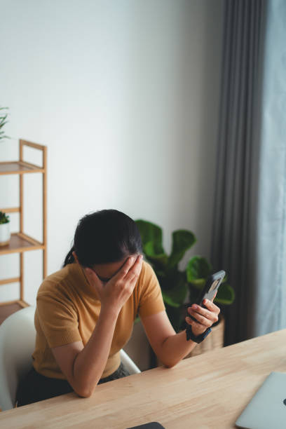 istock Asian woman sitting at home office looking at smartphone screen and having problem. 1631056815