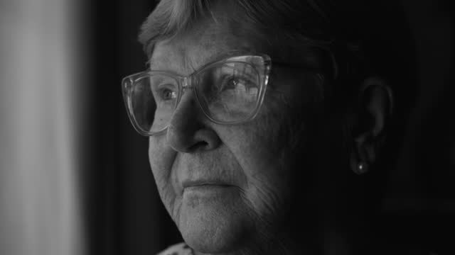 Senior Woman Contemplating in Dramatic Monochrome Scene, Staring Out Home Window in Black and White